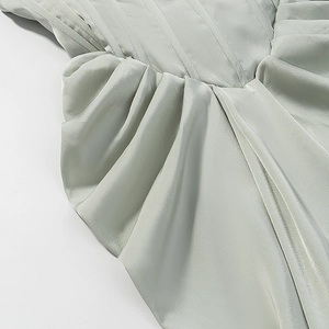 Detailaufnahme der plissierten Satin-Struktur in Salbeigrün für das Neckholder-Maxikleid