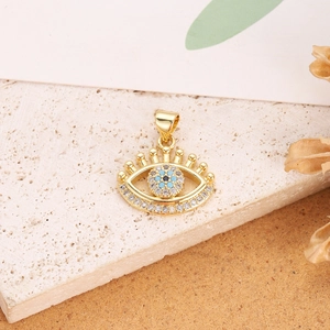 Macro view of gold Evil Eye pendant with blue crystal on a textured stone base