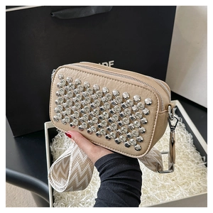 Detail of beige crossbody bag with silver studs and a wide woven shoulder strap