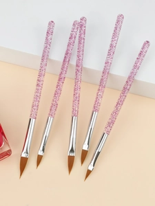 Détail de cinq pinceaux nail art à paillettes roses sur un support géométrique blanc