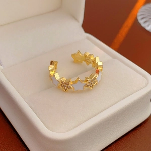 Elegant gold open ring featuring star motifs with white enamel and sparkling crystals