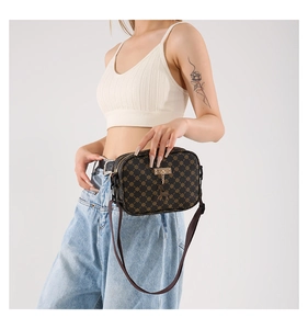 Detail of dark monogram crossbody bag featuring a golden deer pendant and brown strap