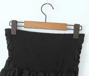 Detailed view of black smocked tube top fabric with elastic gathers and ruffle trim