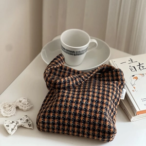 Detail of tweed houndstooth small handbag with orange and black textured woven fabric