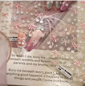 Detailed macro of 5D embossed winter nail stickers with pink bows and snowflake designs