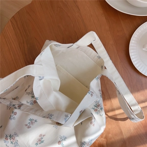 Détail d'un sac cabas floral en coton montrant la poche intérieure sur bois
