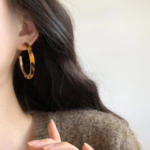Chic tortoiseshell resin C-shaped hoop earrings with gold accents worn by a model