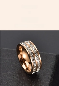 Macro shot of rose gold double-row square-cut crystal ring on dark stone surface