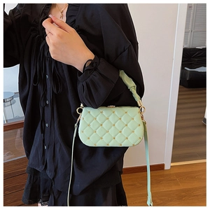 Detail of light green quilted PU leather handbag with metal chain strap on model