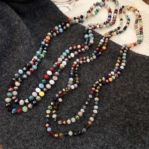 Close-up of bohemian colorful faceted crystal beads long necklace on a fabric background