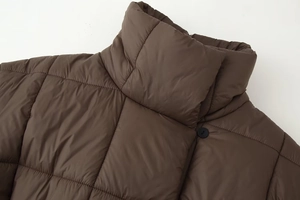 Détail d'une doudoune matelassée marron foncé avec col montant et bouton noir élégant