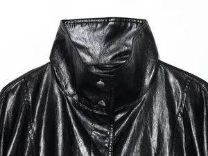 Detail of black leather bomber jacket showing stand-up collar and silver metal snap buttons