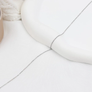 Collier minimaliste en acier inoxydable plaqué or 18K sur un plateau blanc