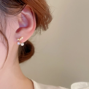 Close-up of a model wearing a gold cherry earring with micro-set zircon and pearl