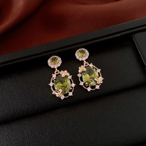 Vue macro de boucles d'oreilles papillon dorées avec zircons vert émeraude sur cuir noir