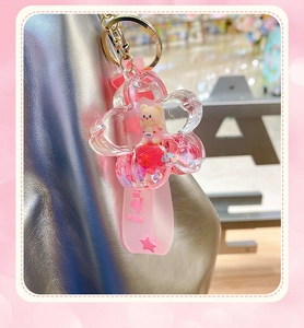 Close-up of pink bear pendant with glitter oil inside hanging on a silver bag strap