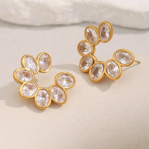 Detailed close-up of gold flower stud earrings with sparkling oval zircon stones