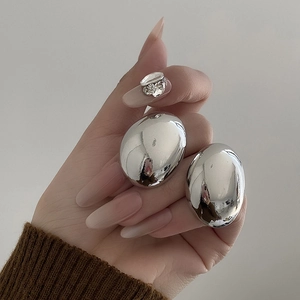 Macro detail of large silver irregular pebble earrings with a polished metallic finish