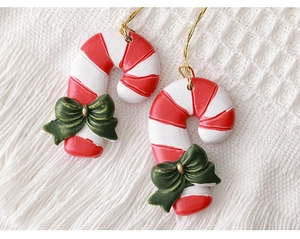 Macro view of candy cane ornament with red and white stripes and green bow detail