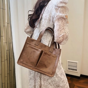 Καφέ τσάντα tote από δερματίνη με μπροστινές τσέπες και λουρί ώμου φορεμένη από μοντέλο