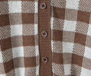 Close-up of brown and white checkered knit cardigan with resin buttons and ribbed placket
