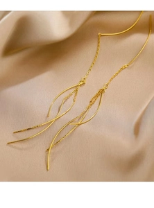 Macro shot of long gold tassel threader earrings on a luxury silk satin background