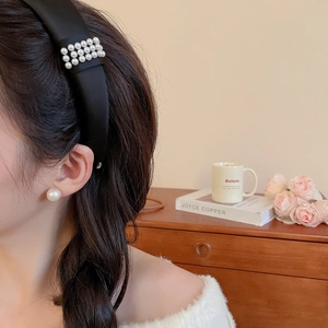 Detail of elegant black satin headband with triple row pearls and matching pearl earrings