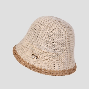 Detail of breathable knit bucket hat with hollow texture and gold bow metal accent