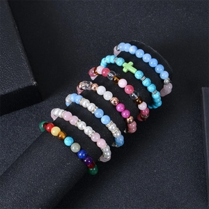Detail of colorful bohemian natural stone beaded bracelets with a green cross charm