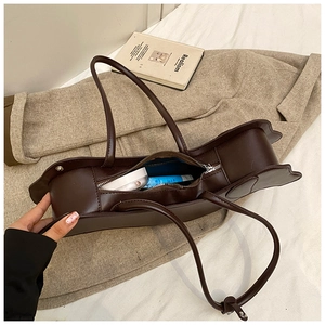 Interior view of brown leather tote bag with wavy rim showing spacious zipper compartment