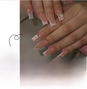 Macro detail of French style press-on nails with 3D white flowers and sparkling rhinestones