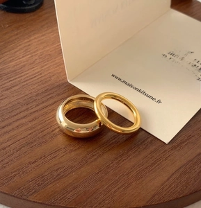 Detail view of gold-plated dome ring and slim band set on a wooden tray surface
