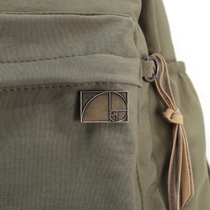 Macro shot of geometric metal badge on a military green nylon bag showing golden ratio design
