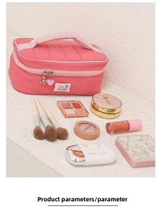 Pink quilted nylon cosmetic bag featuring a wide handle and decorative flower charms