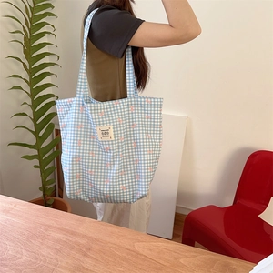 Detail view of blue checkered canvas tote bag with pink bow prints and LOVE label