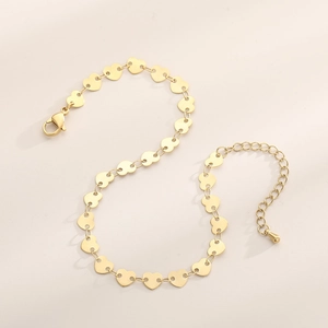 Detailed close-up of golden heart-shaped titanium steel anklet links and lobster clasp