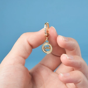 Detailed macro view of gold-plated LOVE pendant earrings with sparkling zircon inlay