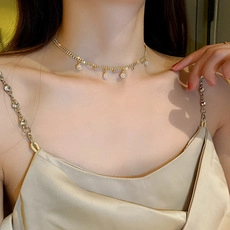 Détail du collier de perles dorées réglable avec pendentif papillon sur tissu en soie