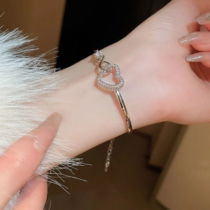 Close-up of a silver hollow heart open bracelet with zircon inlay on a woman's wrist