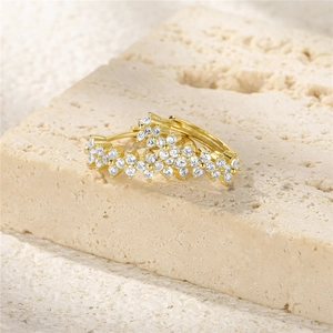 Macro shot of gold S925 silver earrings featuring clustered white zircon flower design