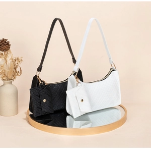 Detail view of woven leather shoulder bags in black and white with mini pouches on a tray