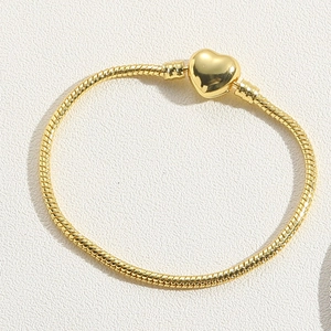 Detail shot of golden heart-shaped clasp and polished snake chain bracelet texture