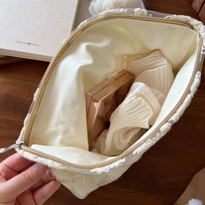 Détail d'une trousse à maquillage en dentelle crème avec palette et espace de rangement