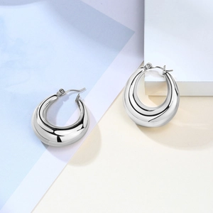 Detailed view of thick silver geometric hoop earrings with polished mirror finish