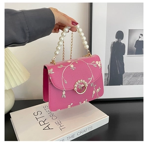 Detail of pink pearl handle bag with floral embroidery and gold chain strap