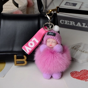 Pink sleeping doll keychain with real fox fur ball and knit hat detail on a luxury bag