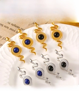 Macro di orecchini a serpente in oro e argento con perle di pietra blu e nere su un vassoio