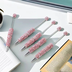 Pink DIY rhinestone pens in a set of five with shiny metal barrels on a desk