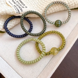 Detailed close-up of five colorful spiral hair ties with heart and star charms on white fabric