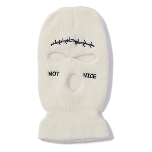 Detail of white knit ski mask featuring black 'NOT NICE' text and abstract patterns
